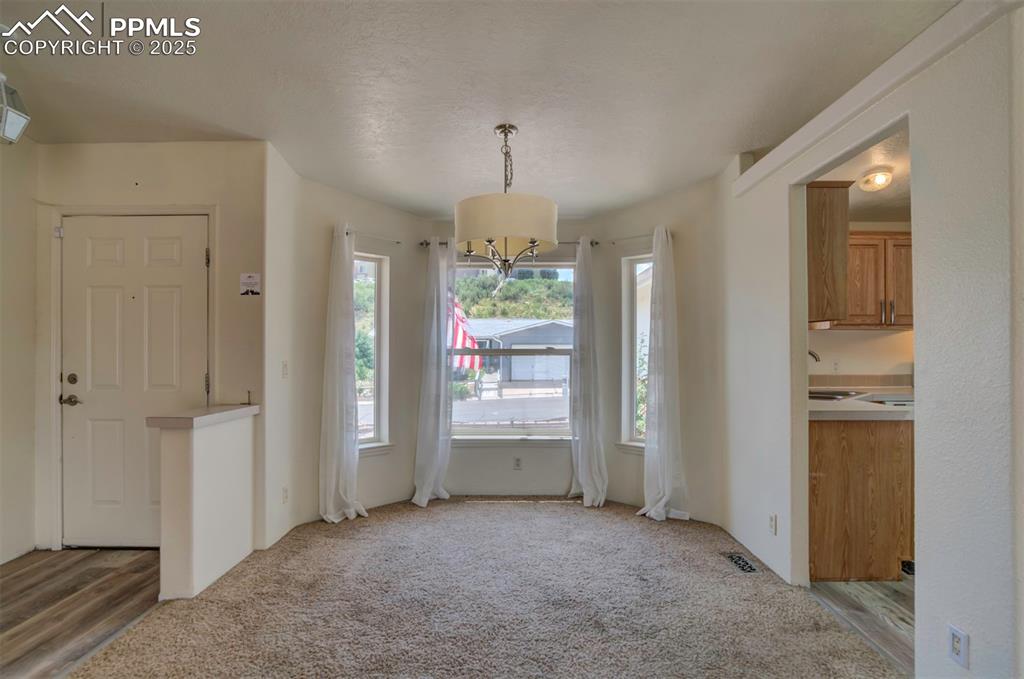 Image 5 of 31: Unfurnished dining area featuring light colored carpet and a chandelier