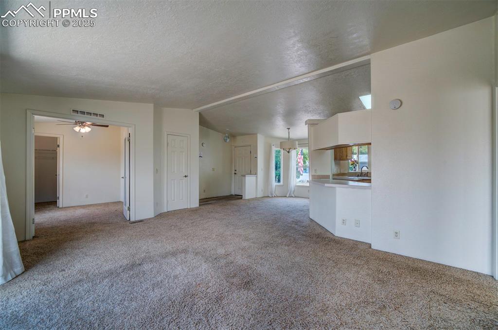 Image 6 of 31: Unfurnished living room with carpet flooring, a textured ceiling, and ceili