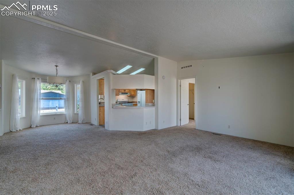 Image 7 of 31: Unfurnished living room featuring a textured ceiling and light colored carp