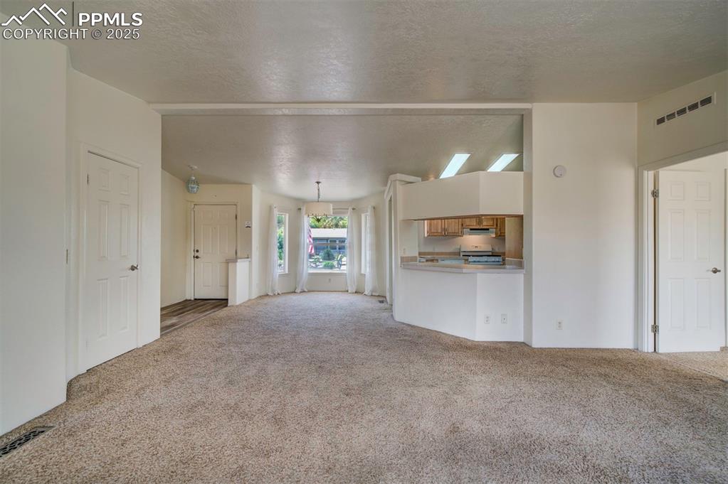Image 8 of 31: Unfurnished living room featuring carpet floors and a textured ceiling