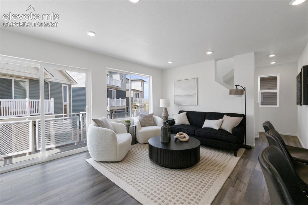 Image 6 of 20: Bright living area featuring wood-finish flooring, recessed lighting, and l