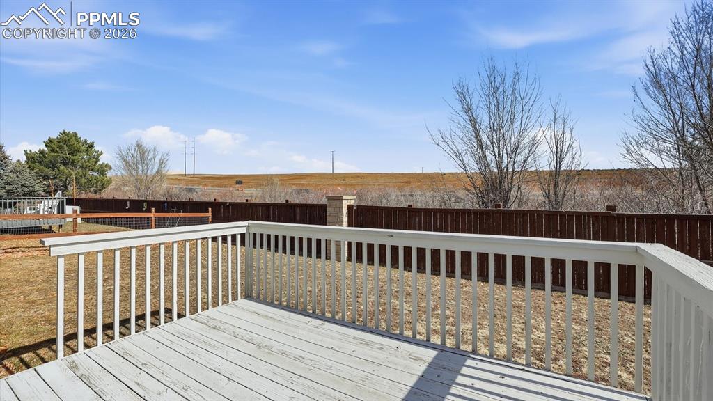 Image 11 of 37: The Backyard Deck overlooks the well manicured fenced yard.