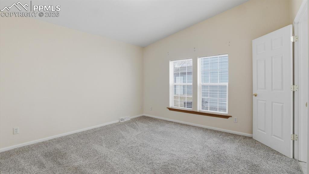 Image 21 of 37: The vaulted Primary Bedroom offers neutral carpet and a large view window.