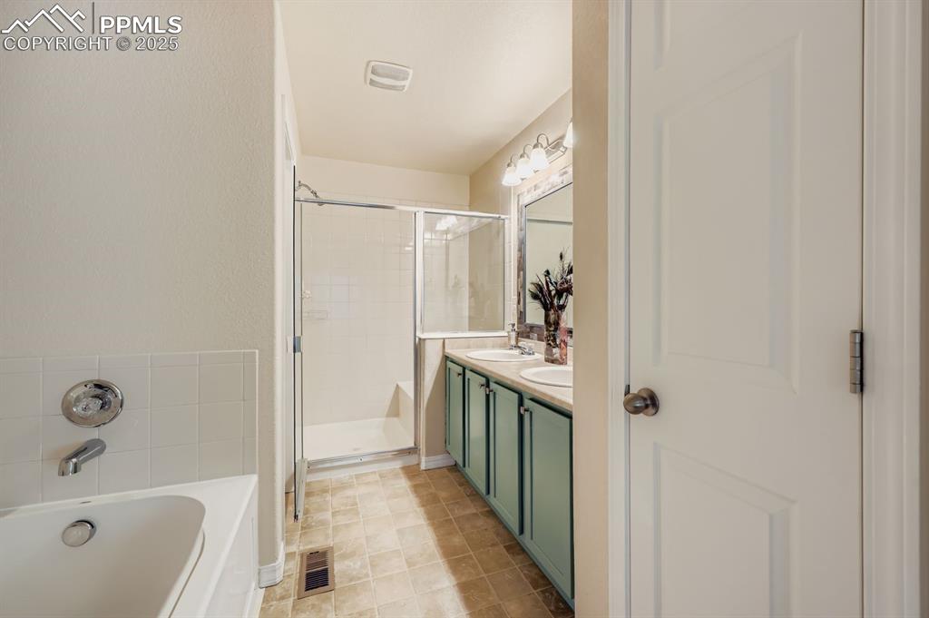 Image 10 of 10: Bathroom featuring double vanity, a bath, a shower stall, and light tile pa