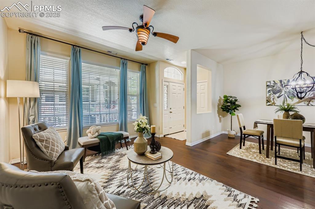 Image 3 of 10: Living room featuring dark wood-style flooring, a ceiling fan, a chandelier