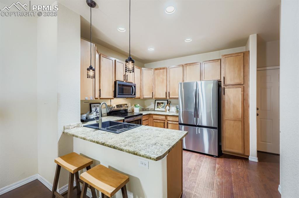 Image 4 of 10: Kitchen with appliances with stainless steel finishes, dark wood-style floo