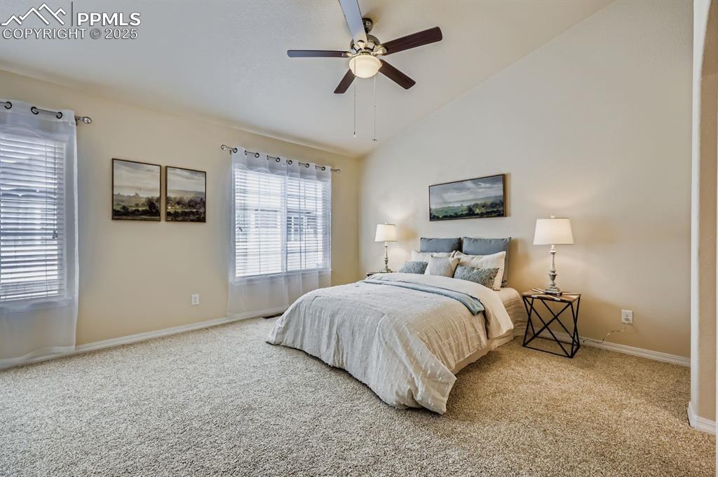 Image 8 of 10: Carpeted bedroom with vaulted ceiling and ceiling fan