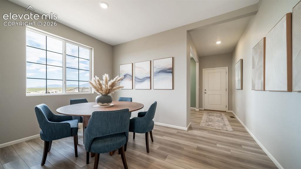 Image 12 of 39: Bright dining area featuring a large grid-pattern window, wood-finish floor