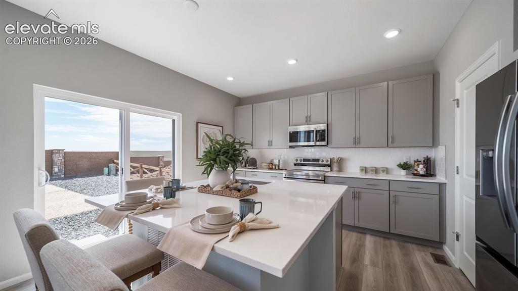 Image 15 of 39: Contemporary kitchen featuring an oversized island with white countertop, s