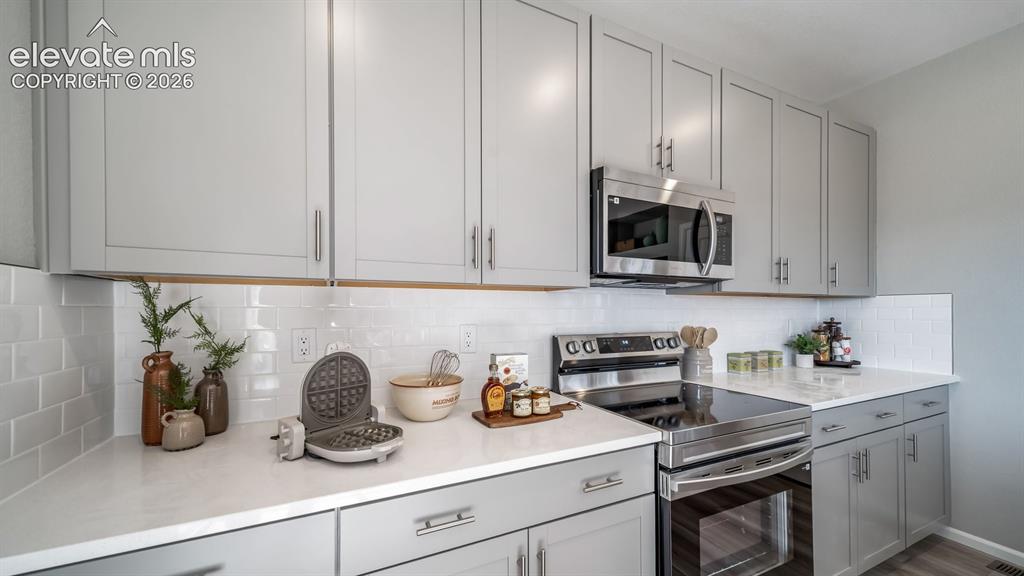 Image 24 of 39: Modern kitchen featuring light gray cabinetry, white subway tile backsplash