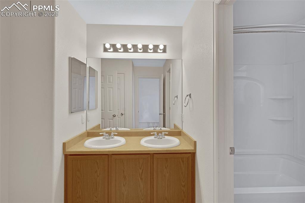Image 17 of 24: Bathroom featuring double vanity and bathing tub / shower combination