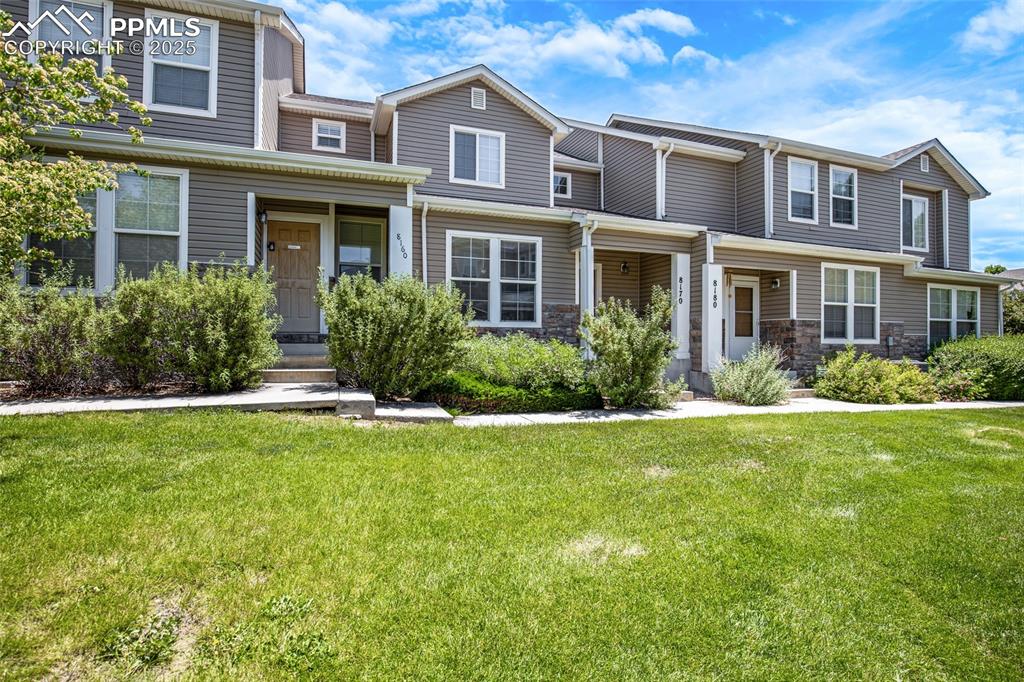 Image 3 of 24: Townhome / multi-family property featuring a front lawn and stone siding