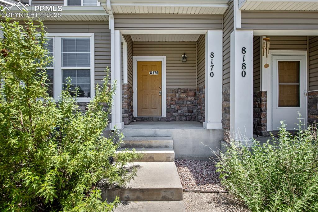 Image 4 of 24: Entrance to property featuring stone siding and covered porch