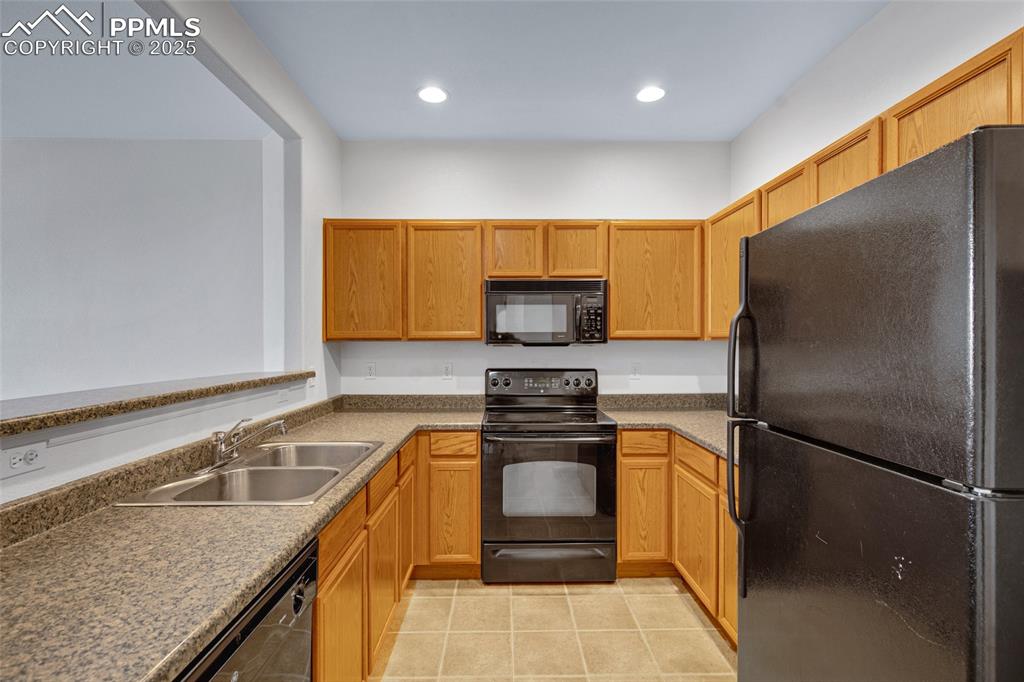 Image 9 of 24: Kitchen featuring black appliances, light tile patterned floors, and recess