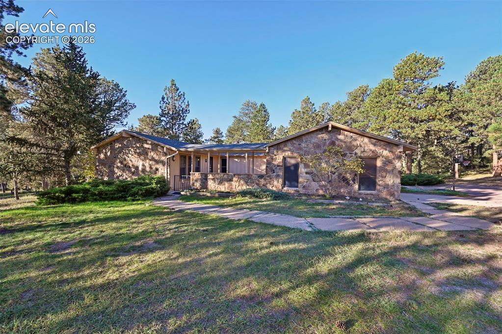 Caption: Stone exterior residence with a covered porch and surrounding mature trees
