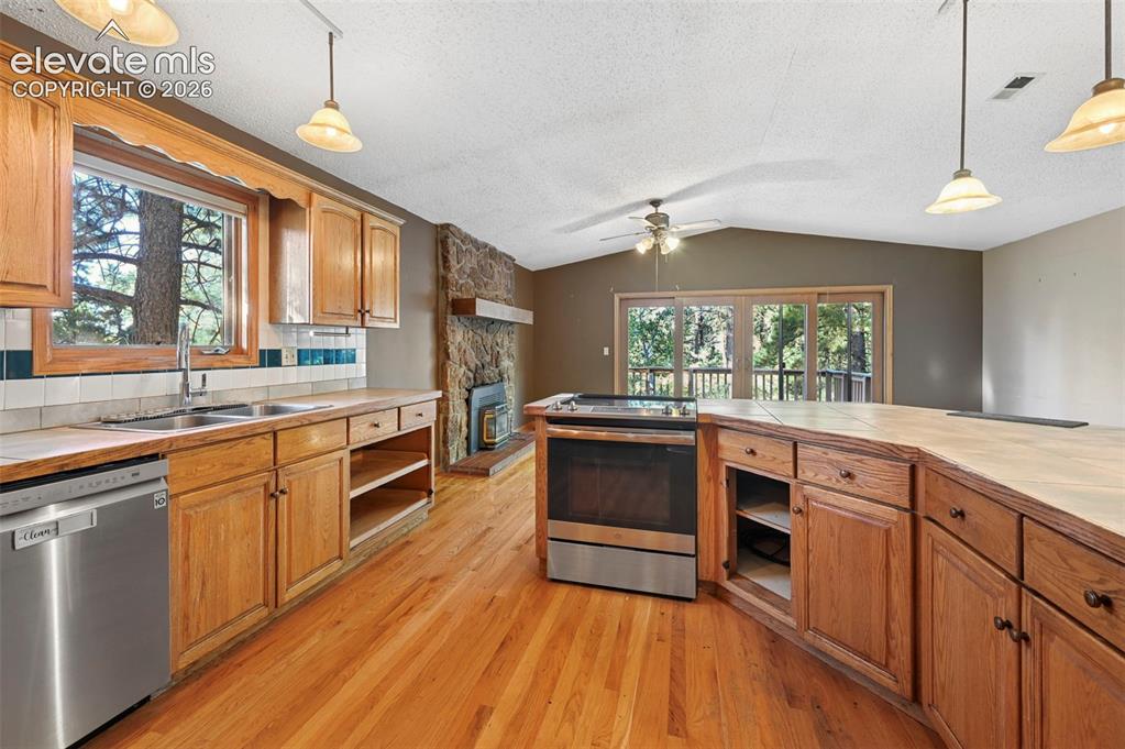 Image 12 of 47: Hardwood flooring, wood-finish cabinetry, stainless steel dishwasher, stone
