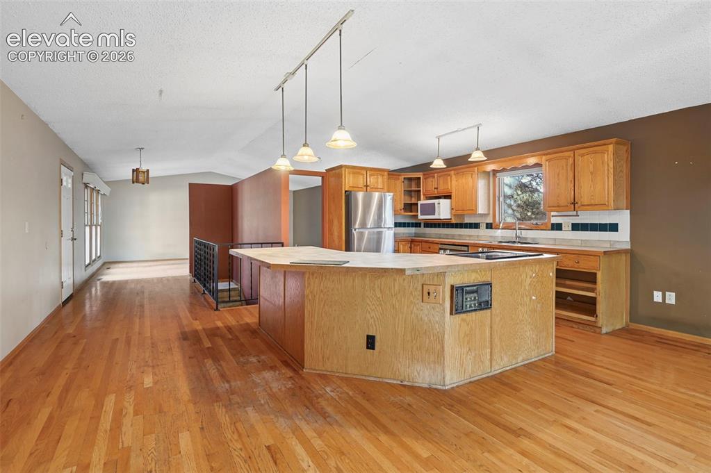 Image 13 of 47: Hardwood flooring throughout, kitchen island with built-in cooktop, stainle