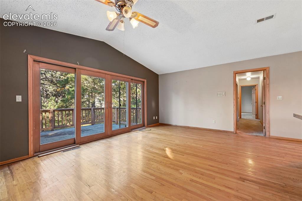 Image 20 of 47: Vaulted ceiling with a ceiling fan, wood-finish flooring, and sliding glass