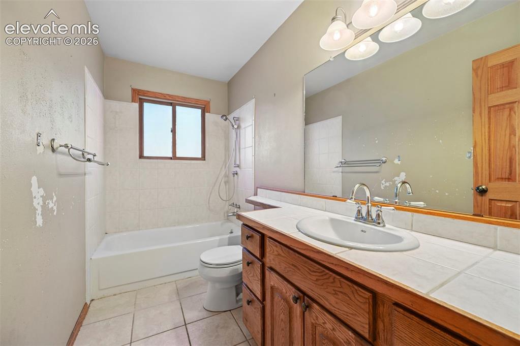 Image 23 of 47: Vanity with wood cabinetry, white tile countertop, and integrated sink