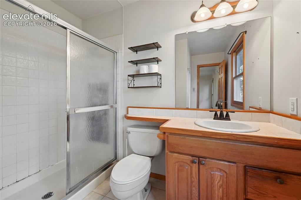 Image 26 of 47: Wood-finish vanity with an integrated sink, a three-light vanity fixture, a