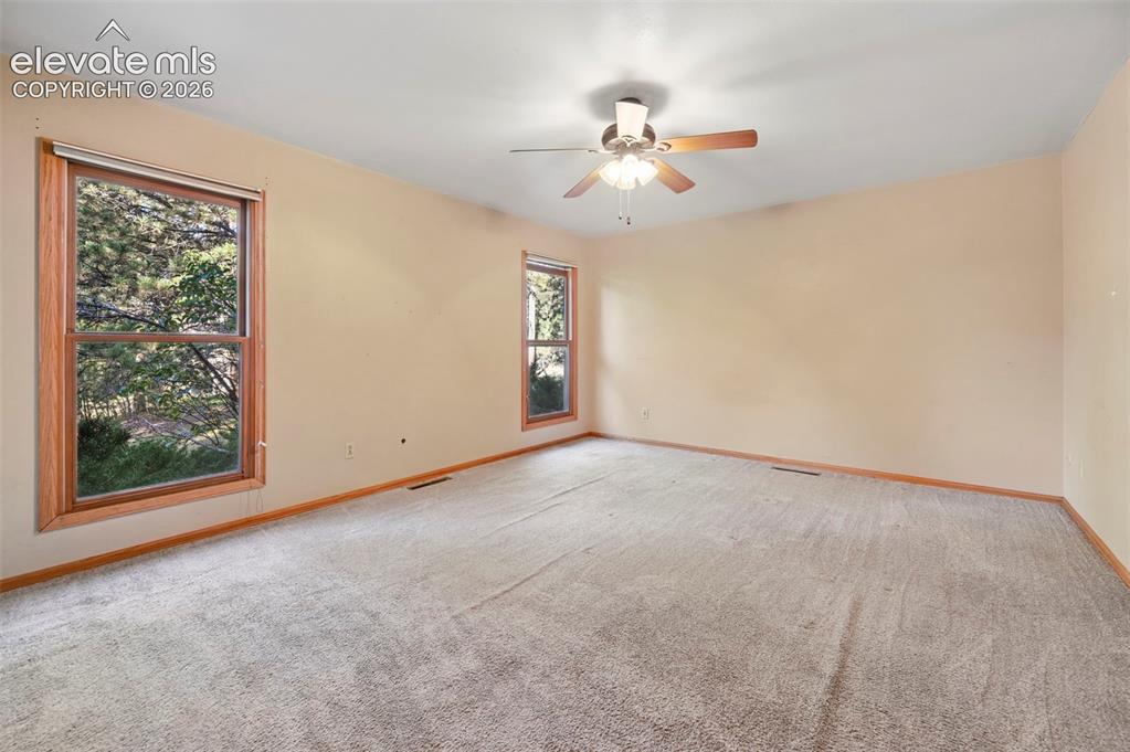 Image 31 of 47: Two large windows with wood-finish trim, ceiling fan with integrated lighti