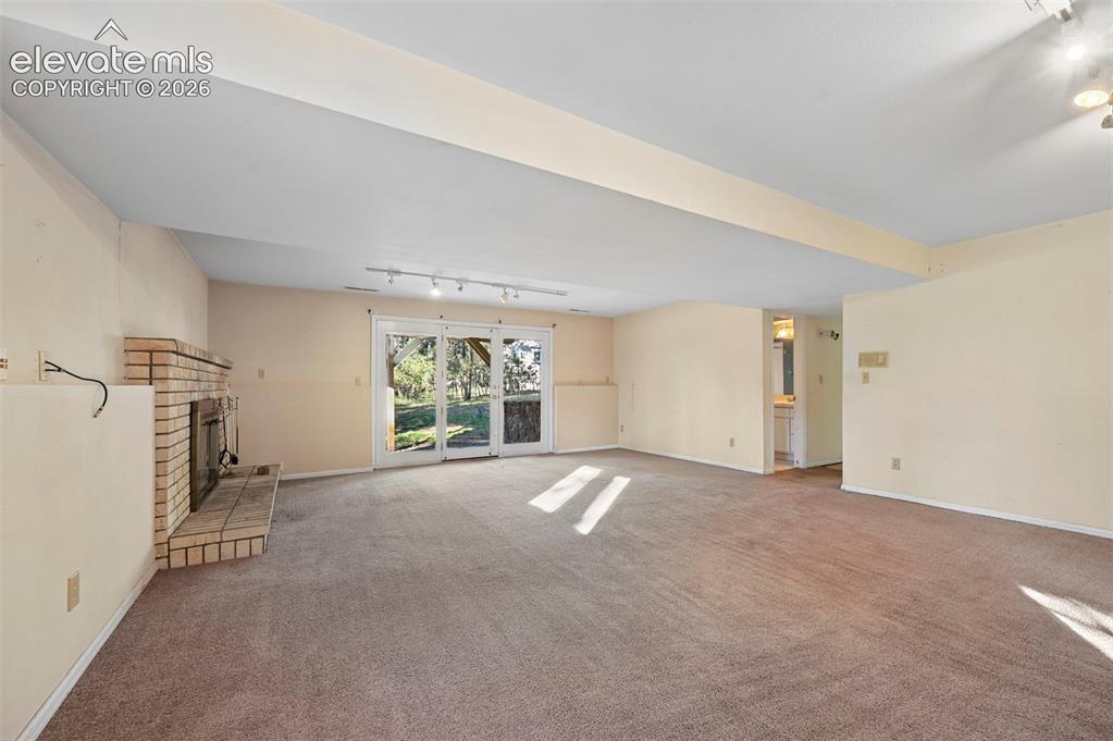 Image 32 of 47: Expansive room featuring a brick fireplace, track lighting, and sliding gla