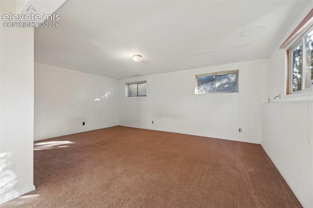 Image 39 of 47: Expansive room featuring carpet flooring, white paneled walls, and multiple
