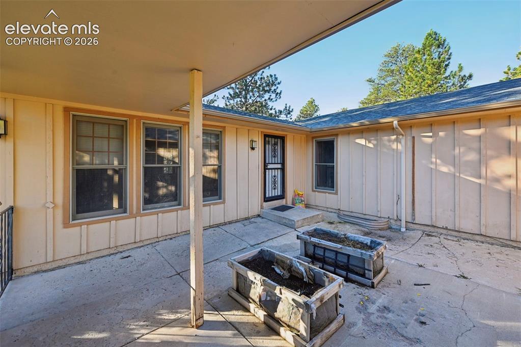 Image 8 of 47: Covered patio area with concrete surfacing and built-in planters