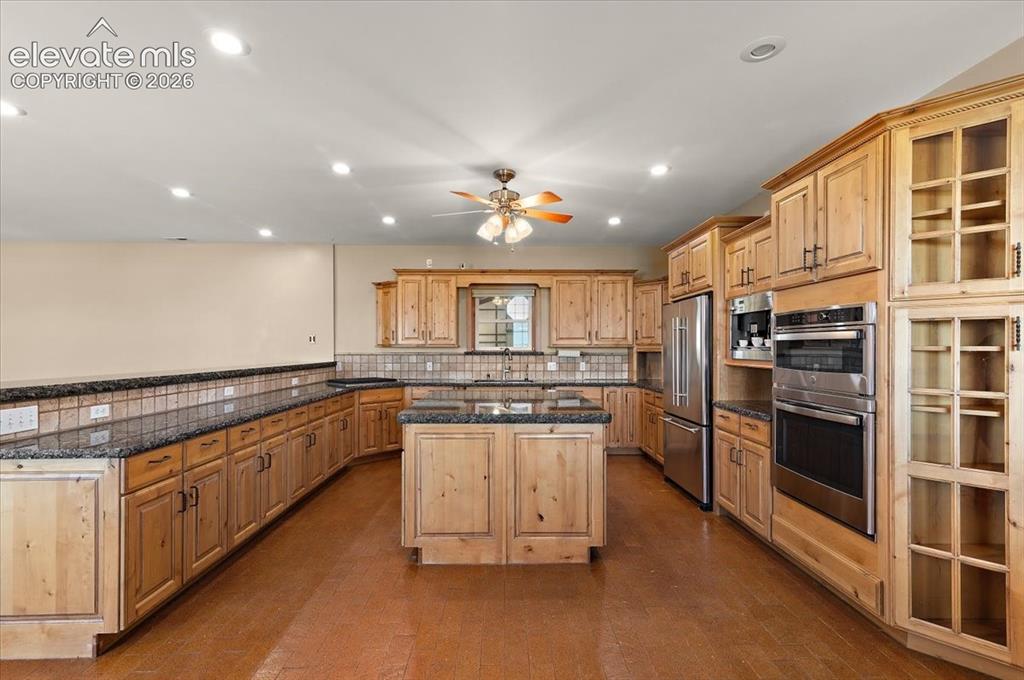 Image 7 of 50: Granite countertops surfaces on cabinets and Island, stovetop, microwave an