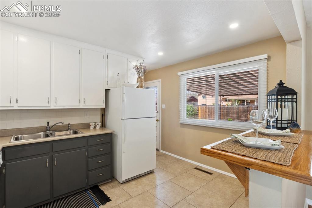 Image 9 of 34: Kitchen featuring tile flooring with breakfast bar and access to back door