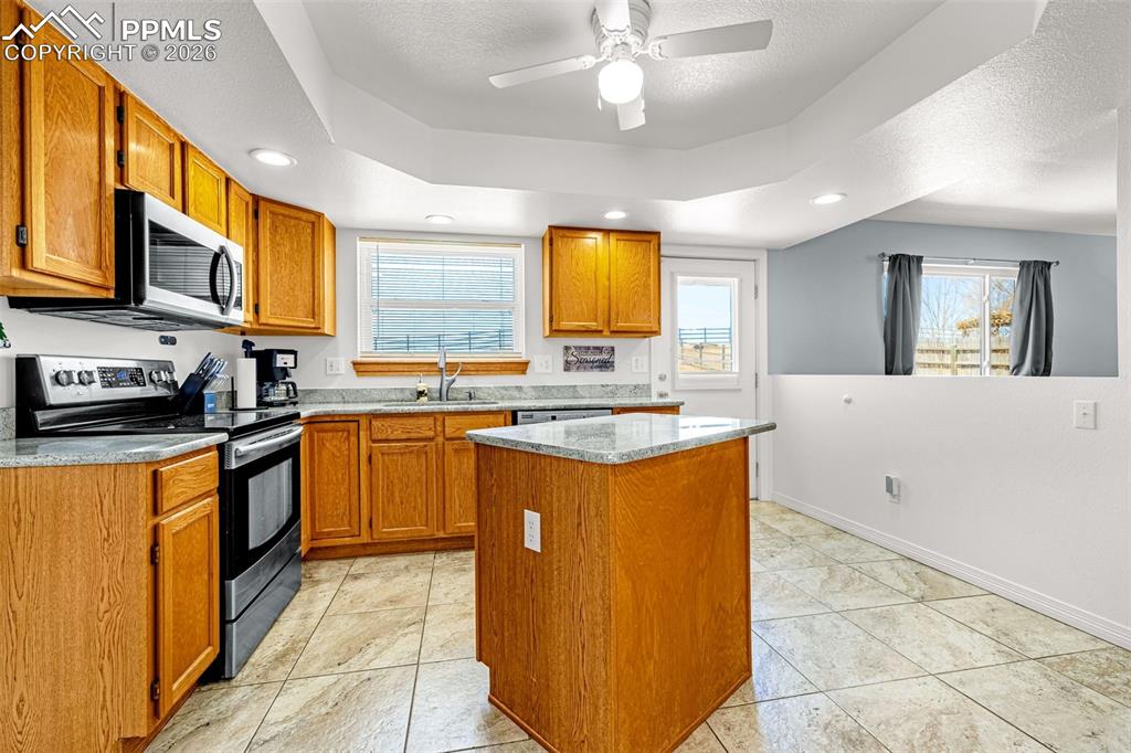 Image 8 of 42: Kitchen featuring stainless steel appliances, a center island, a ceiling fa