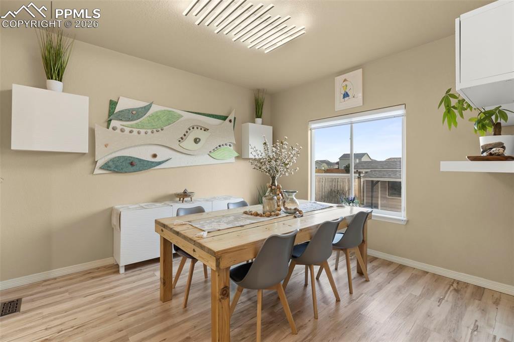Image 13 of 50: Office space with light wood-style floors and hanging lights