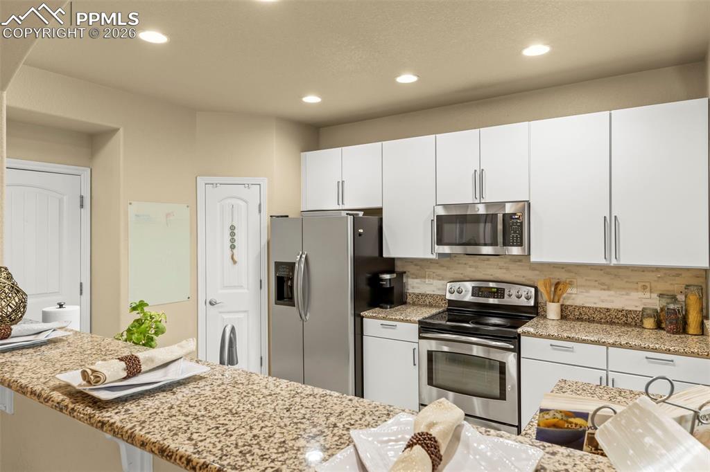 Image 18 of 50: Living area with arched walkways, light wood-style floors, and ceiling fan