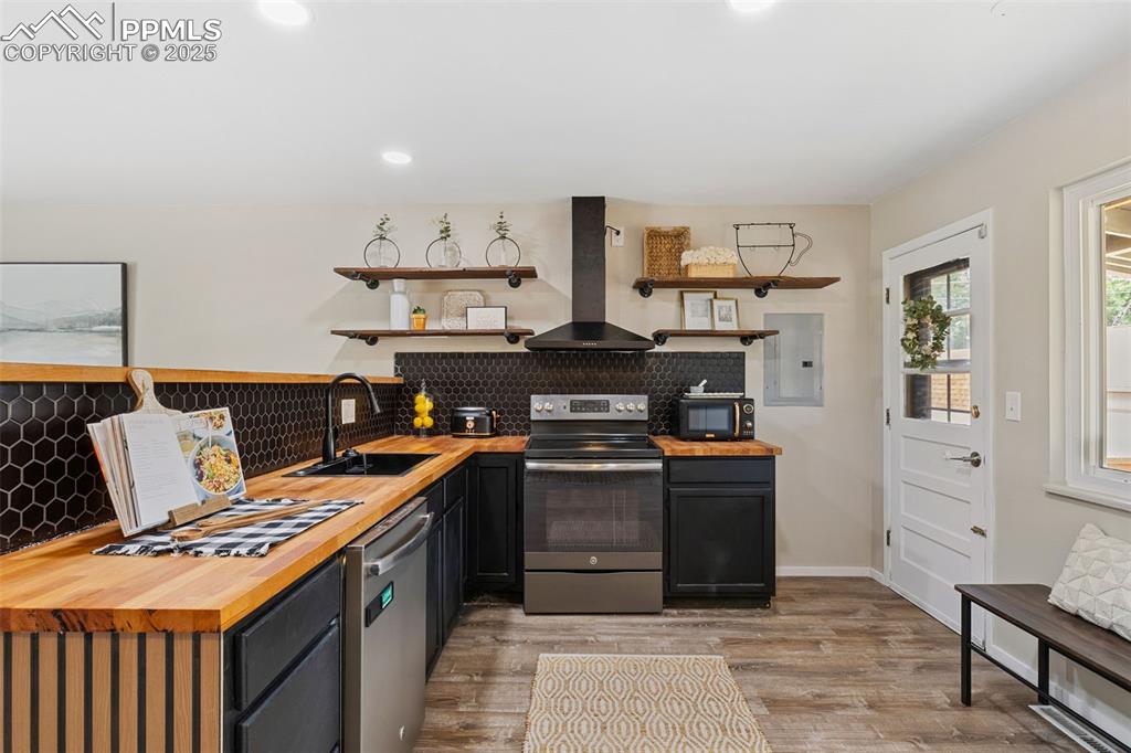Image 10 of 38: Kitchen with butcher block counters, open shelves, stainless steel applianc