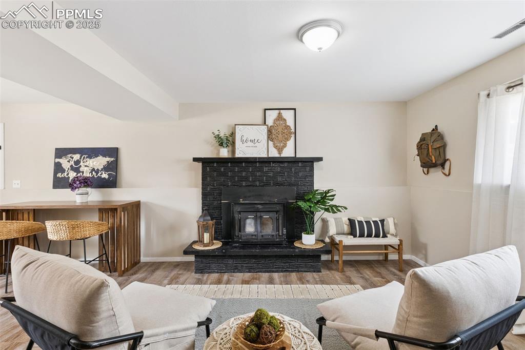 Image 20 of 38: Living area featuring wood finished floors and a brick fireplace