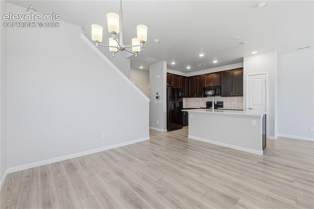 Image 11 of 42: Open-concept living space featuring wood-finish flooring, a modern chandeli