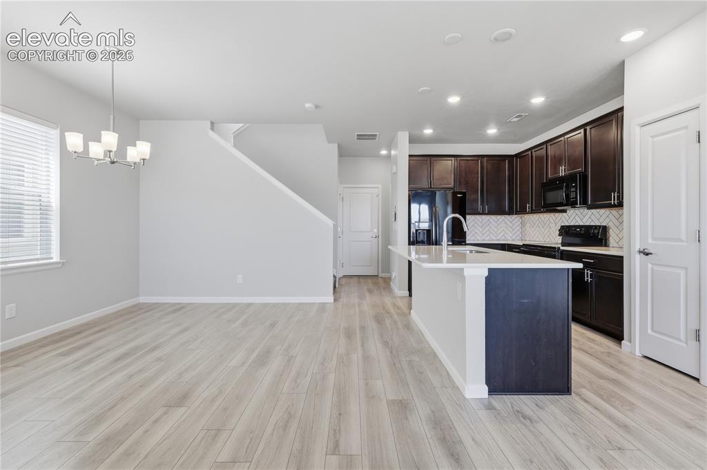 Image 12 of 42: Open-concept living area with light wood-finish flooring