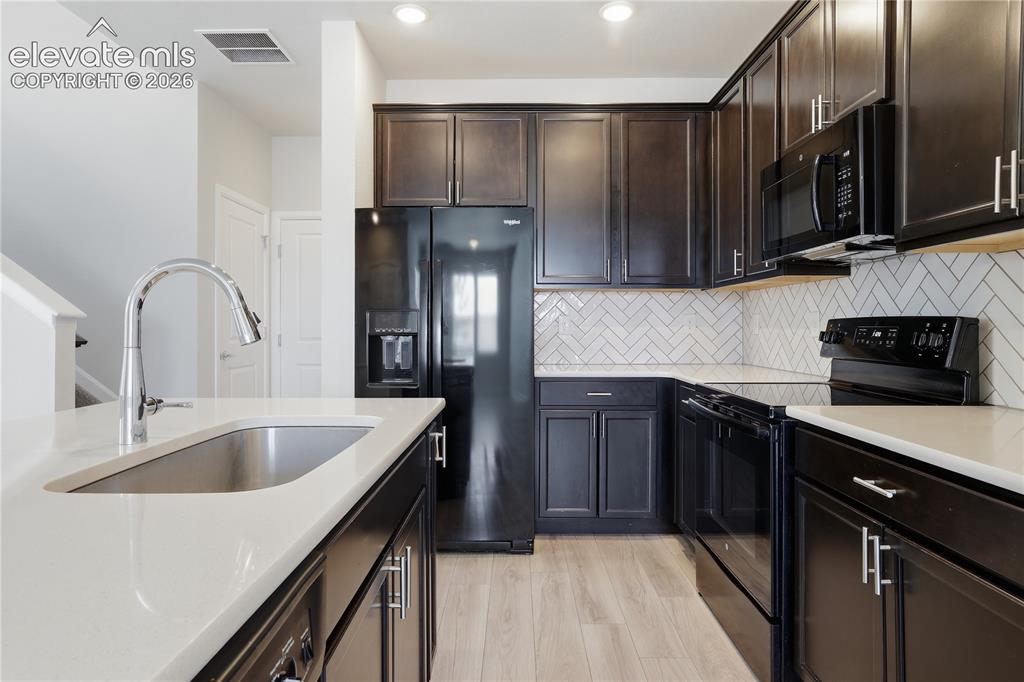 Image 13 of 42: Kitchen featuring dark wood cabinetry, light-toned countertops, and a white