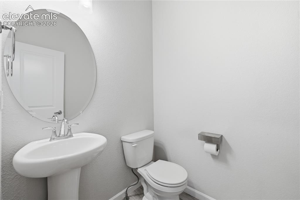 Image 18 of 42: Pedestal sink with chrome faucet, oval mirror, and light gray walls