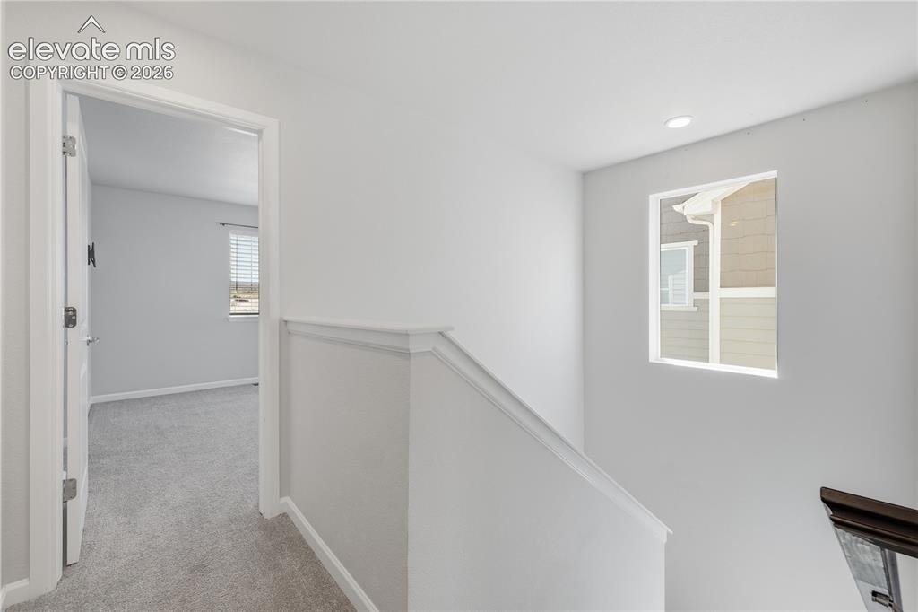 Image 19 of 42: Upper-level hallway with light gray walls, white trim, and a window providi