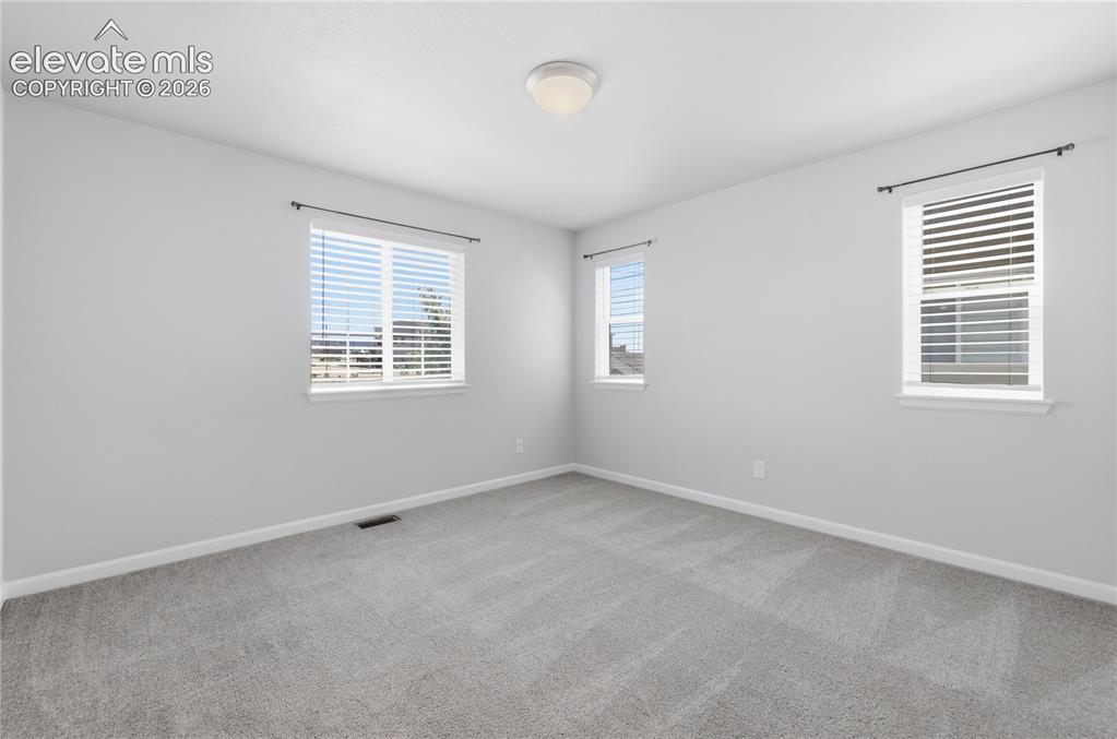 Image 21 of 42: Neutral tone wall paint, light gray carpet flooring, multiple windows with