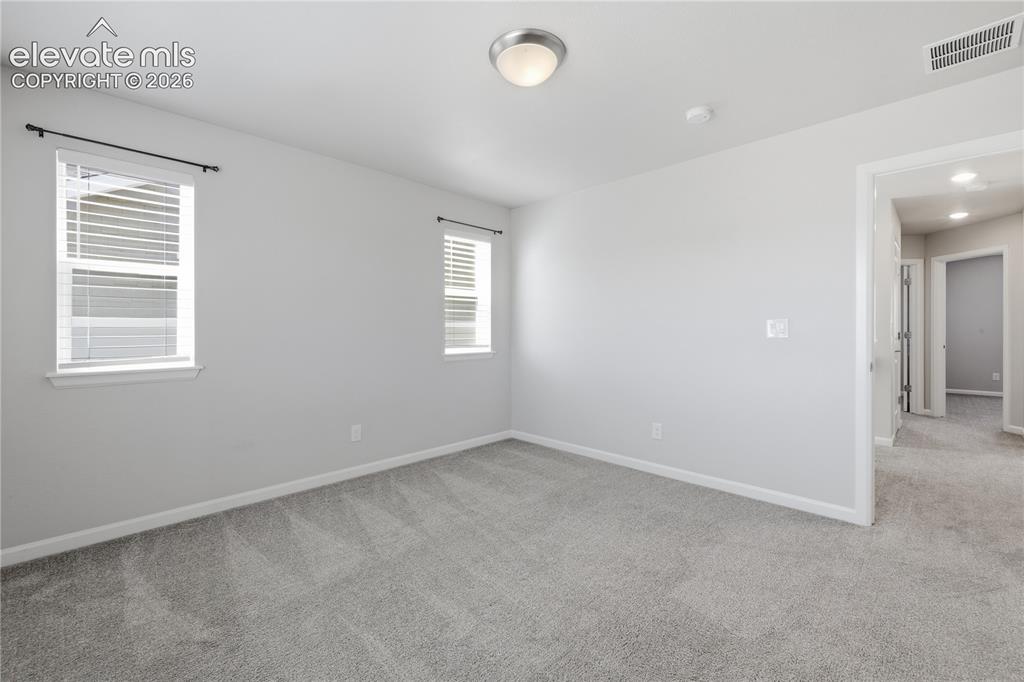 Image 23 of 42: Spacious interior room featuring plush gray carpeting, neutral wall finishe