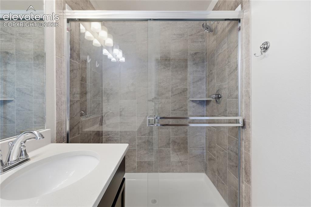 Image 26 of 42: Bathroom featuring a shower with glass enclosure, tiled walls, and a built-