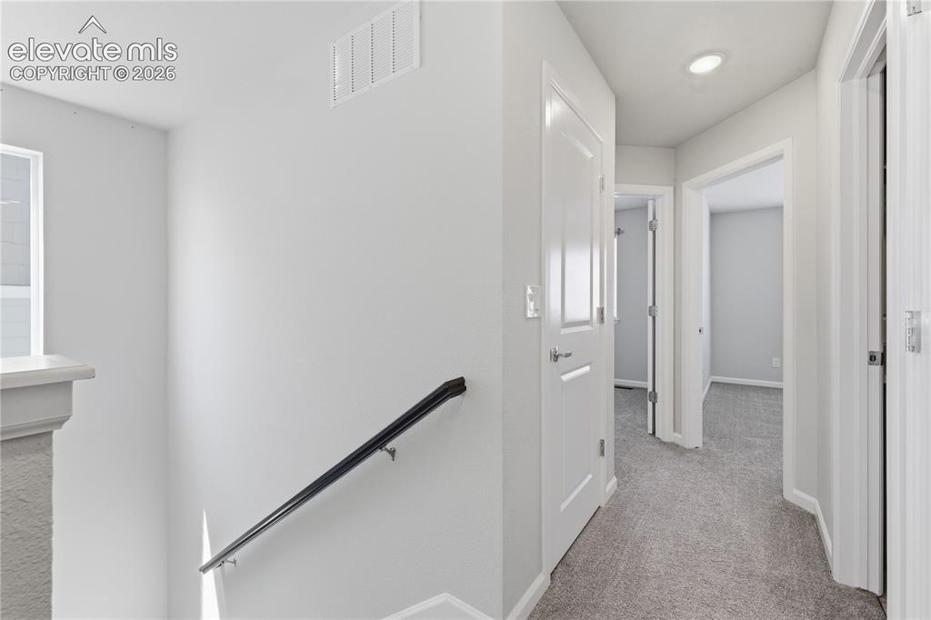 Image 28 of 42: Upper-level hallway with neutral carpeting and recessed lighting