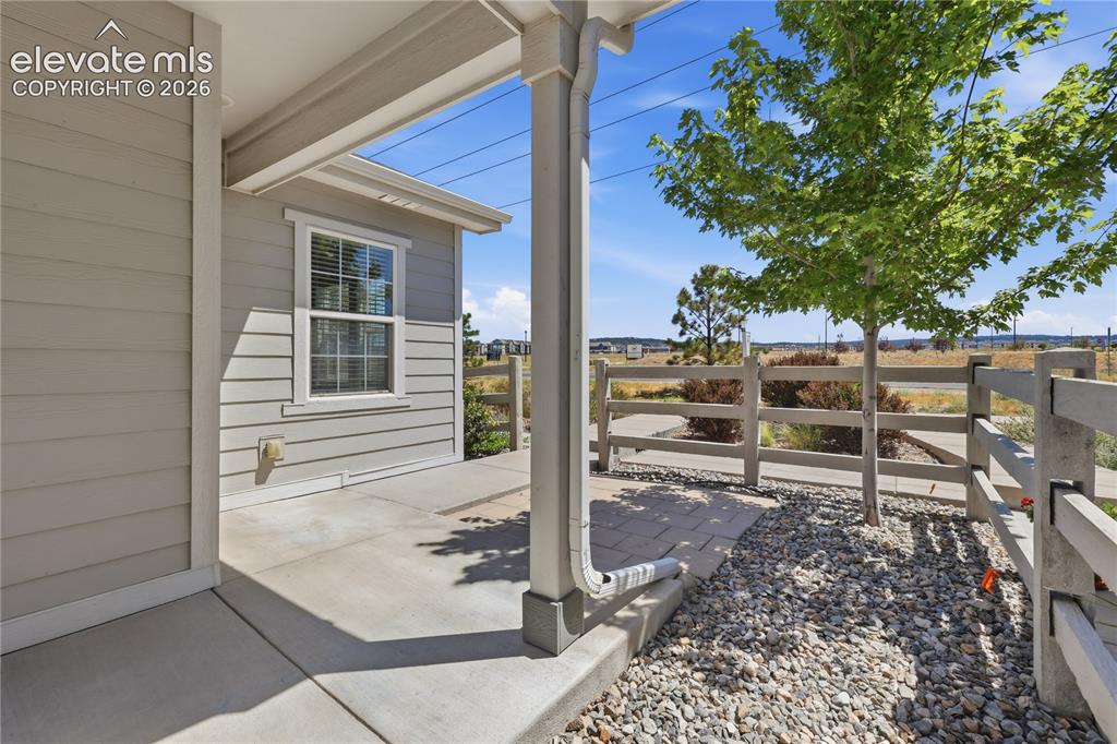 Image 37 of 42: Covered concrete patio with horizontal siding and a white-framed window