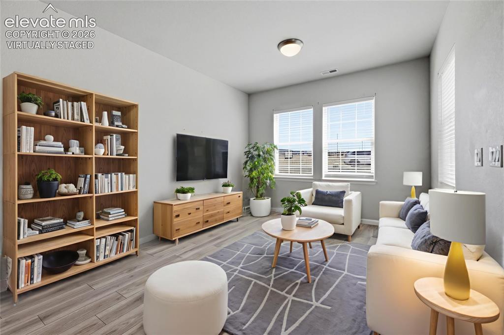 Image 4 of 42: Bright living area featuring wood-finish flooring, light grey wall tones, a