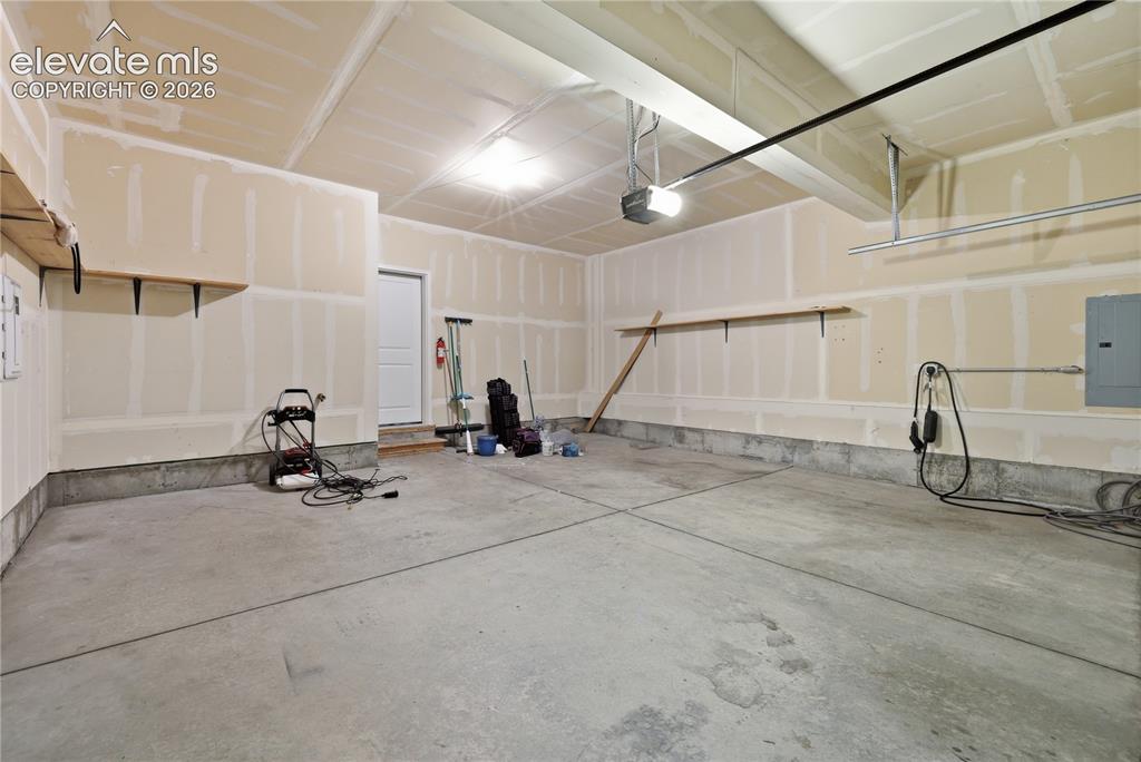 Image 41 of 42: Spacious garage featuring a concrete floor, built-in shelving, an overhead