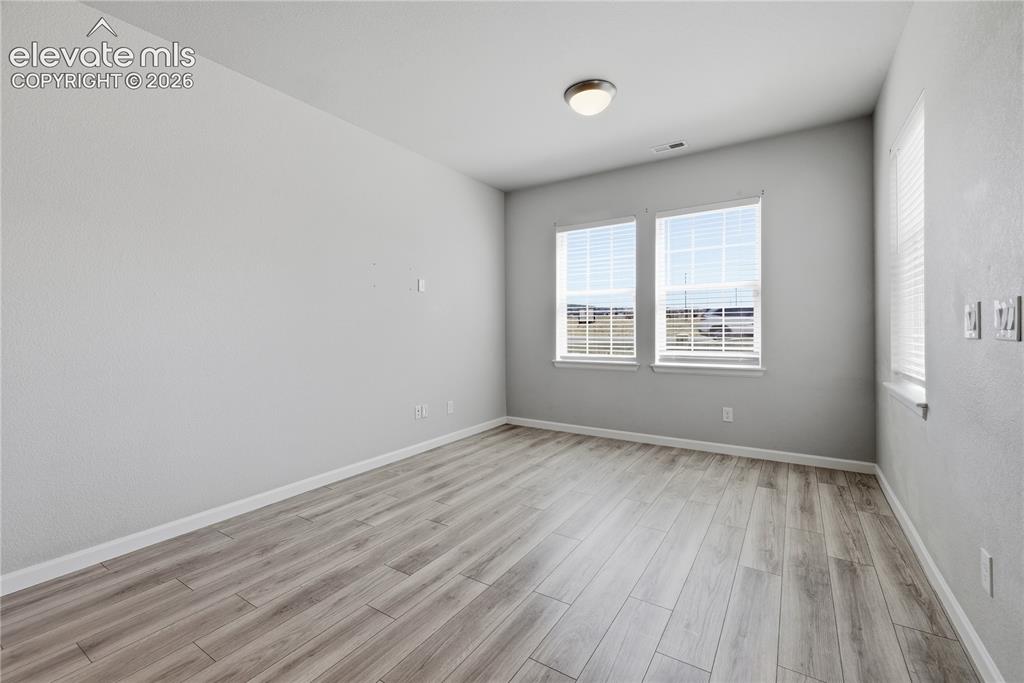 Image 5 of 42: Spacious room featuring wood-finish flooring, light gray wall tones, and mu
