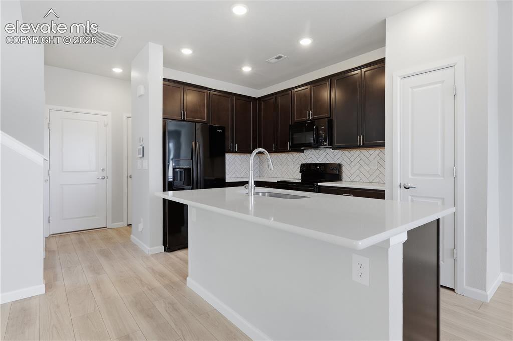 Image 8 of 42: Modern kitchen featuring a light-toned island with an integrated sink, dark