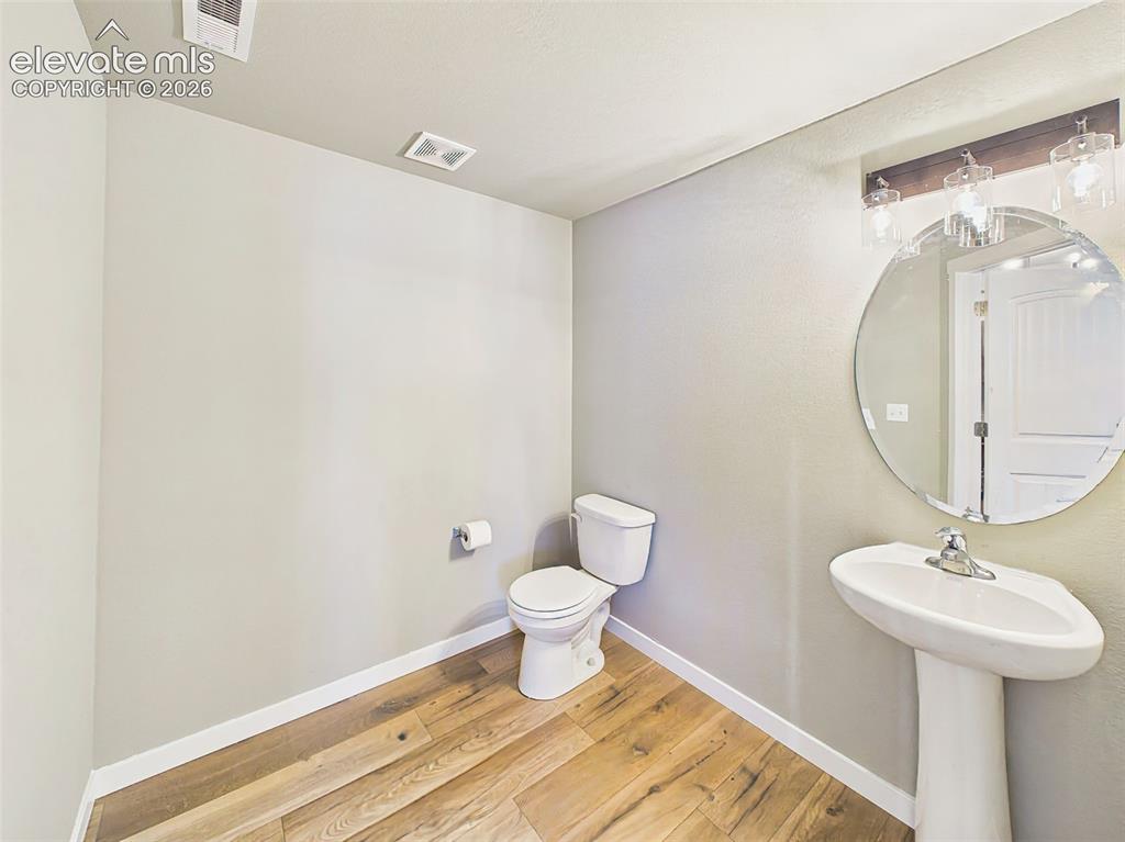 Image 12 of 40: Convenient main-level powder room with pedestal sink and contemporary finis